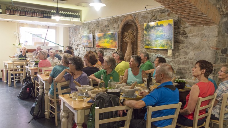 gruppe med mennesker som sitter ved bordet for � spise det de har laget p� pestokurs